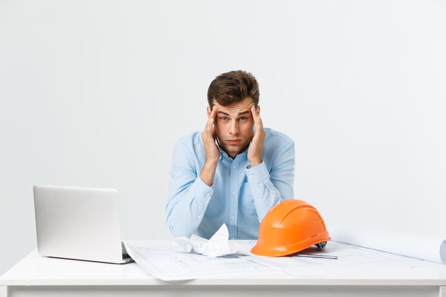 Man sitting at desk looking overwhelmed 