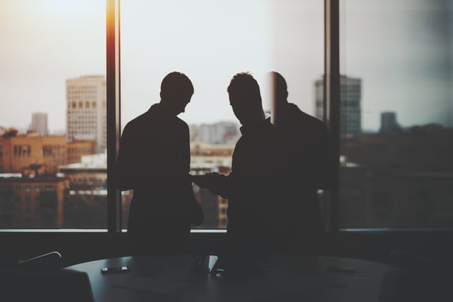 two people standing near a window 